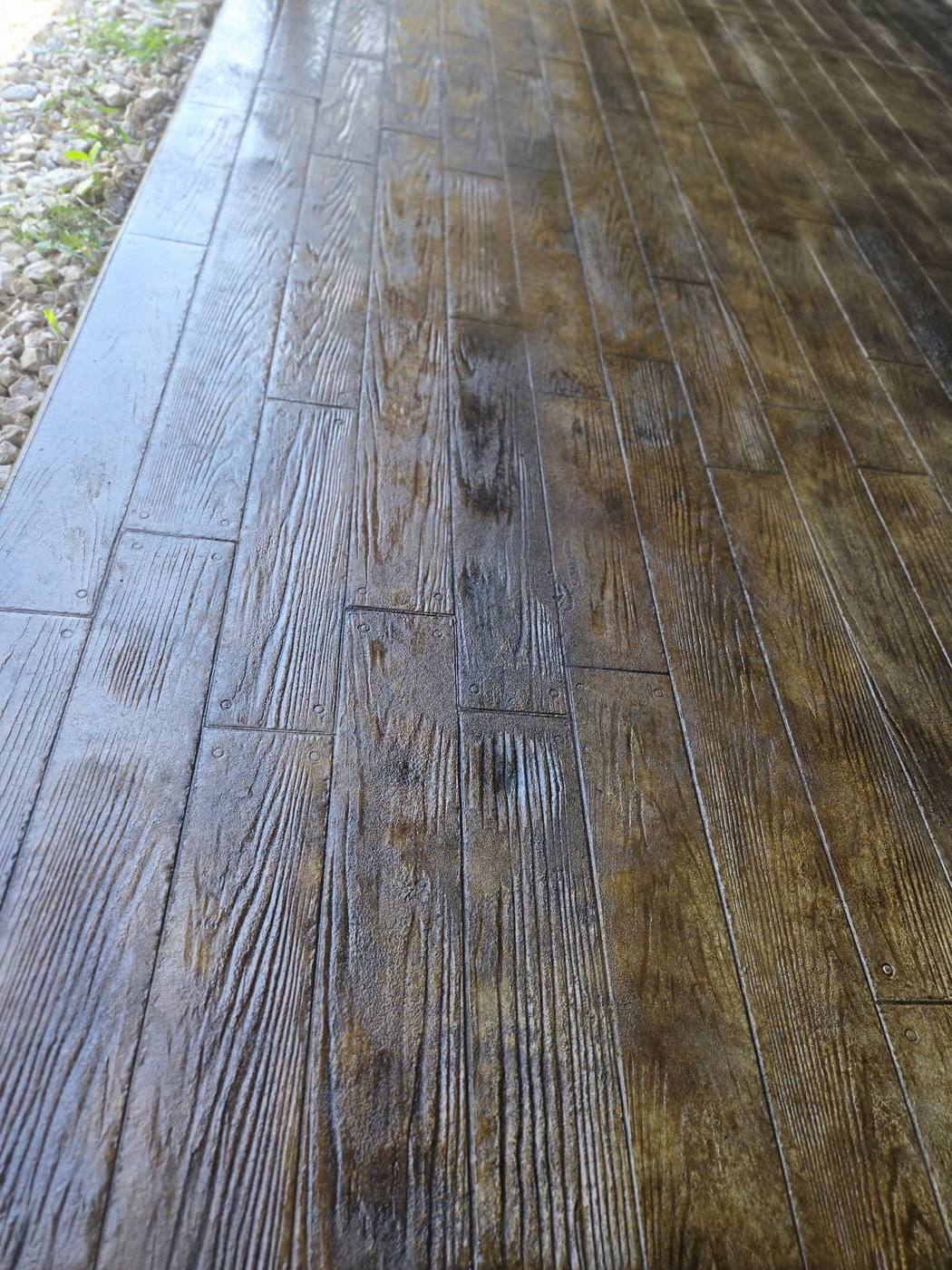 Wood-plank-pattern stamped concrete walkway with plank grain and nail detailing